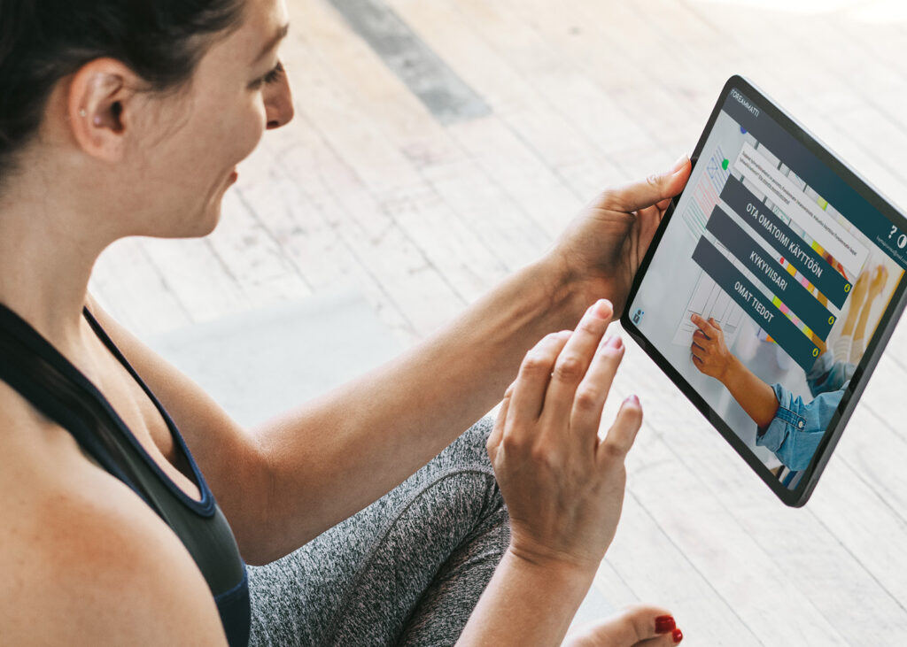 Saat Omatoimi-palvelun käyttöösi vahvan tunnistautumisen avulla ForeAmmatissa. Kuvassa tummahiuksinen naisoletettu joogavaatteissa on painamassa tabletin ruudulla Ota Omatoimi käyttöön painiketta ForeAmmatin etusivulla.